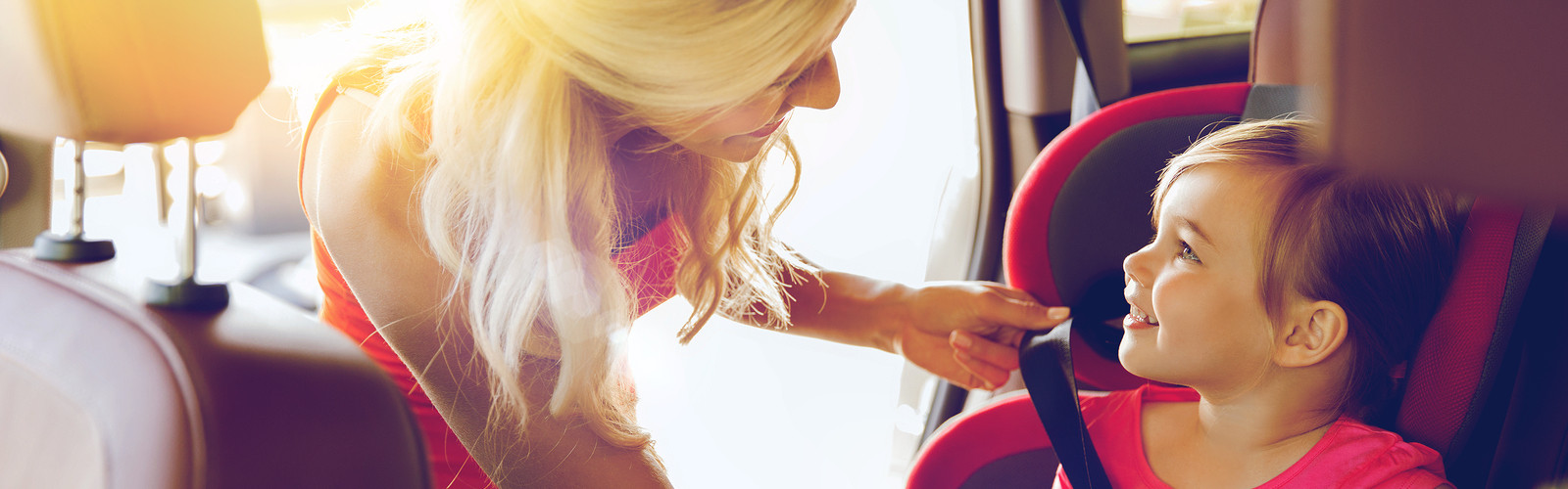 happy mother fastening child with car seat belt