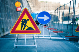 Work in progress. Roadworks, road signs. Men at work. Some signs signage for work in progress on urban street. Barriers and road signs. Silhouette of a worker at work. Right arrow.