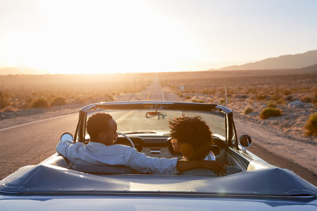 Rear View Of Couple On Road Trip Driving Classic Convertible Car